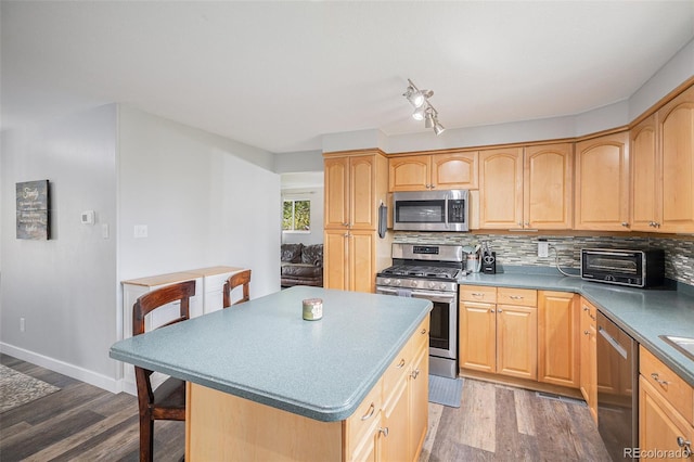 kitchen with wood finished floors, appliances with stainless steel finishes, and decorative backsplash