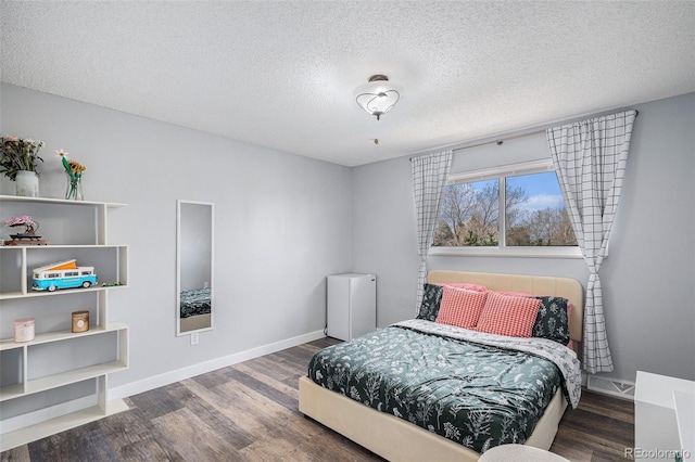 bedroom with wood finished floors, a textured ceiling, and baseboards