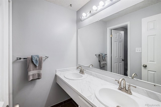 bathroom featuring double vanity, a textured ceiling, tile patterned flooring, and a sink