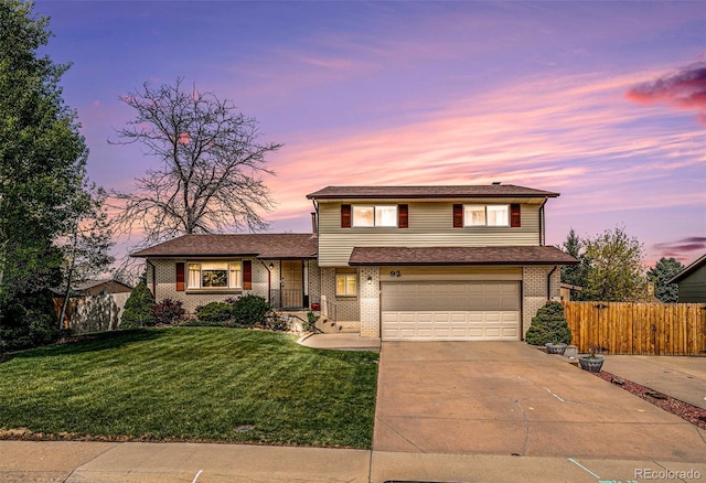 tri-level home with fence, a front lawn, an attached garage, driveway, and brick siding