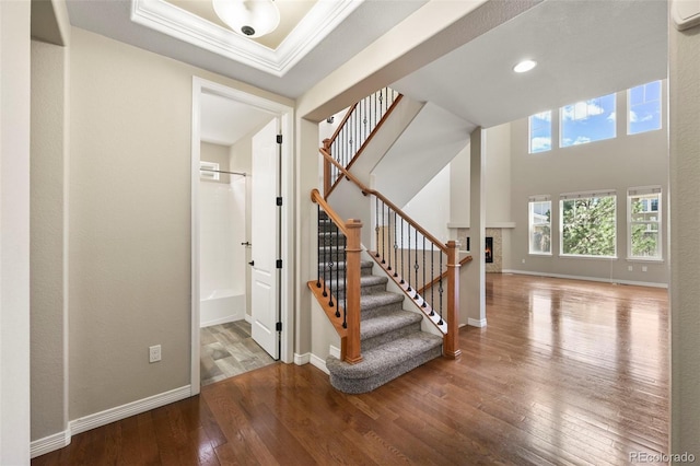 19782 W 59th Ave, Golden, CO 80403 - staircase featuring hardwood / wood-style flooring, crown molding, baseboards, a lit fireplace, and a wall mounted air conditioner