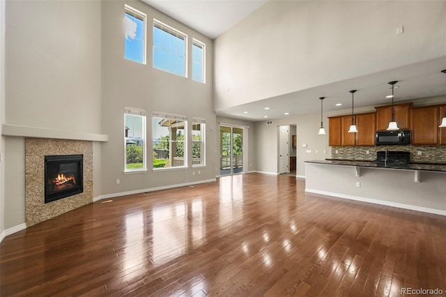 19782 W 59th Ave, Golden, CO 80403 - unfurnished living room with dark wood-style floors, a fireplace, a towering ceiling, and baseboards