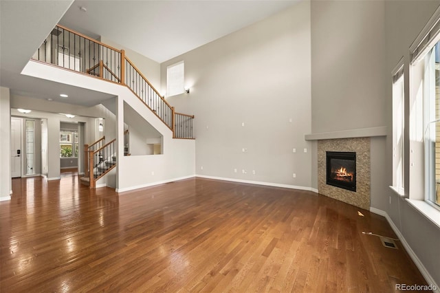 19782 W 59th Ave, Golden, CO 80403 - unfurnished living room with a high ceiling, wood finished floors, a tiled fireplace, stairs, and baseboards