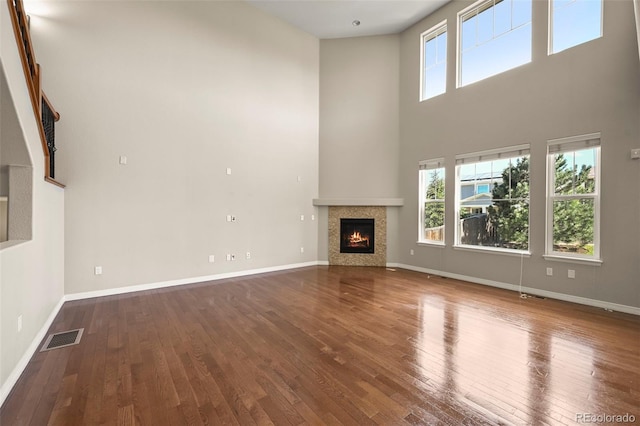 19782 W 59th Ave, Golden, CO 80403 - unfurnished living room with hardwood / wood-style flooring, a towering ceiling, baseboards, and a fireplace