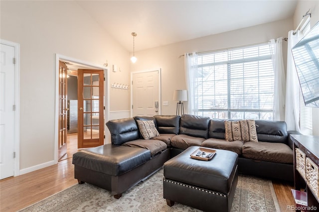 living room with vaulted ceiling, light hardwood / wood-style floors, and french doors