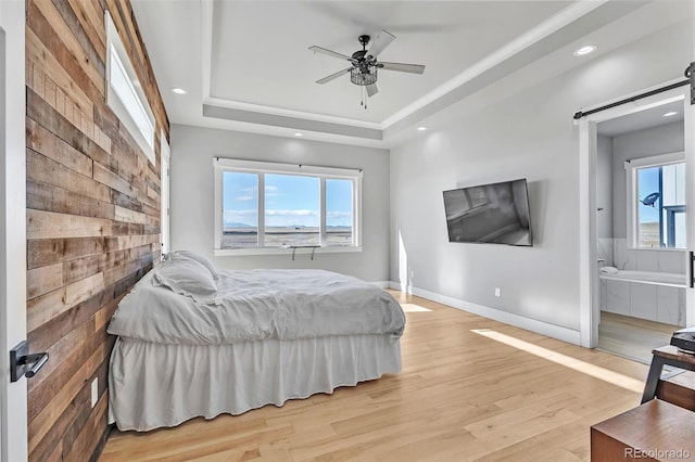 7668 Buckskin Ranch Vw, Peyton, CO 80831 - bedroom featuring a barn door, ensuite bathroom, a tray ceiling, light wood finished floors, and baseboards