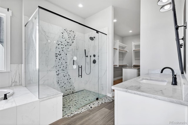 7668 Buckskin Ranch Vw, Peyton, CO 80831 - bathroom featuring a marble finish shower, recessed lighting, wood finished floors, a garden tub, and vanity