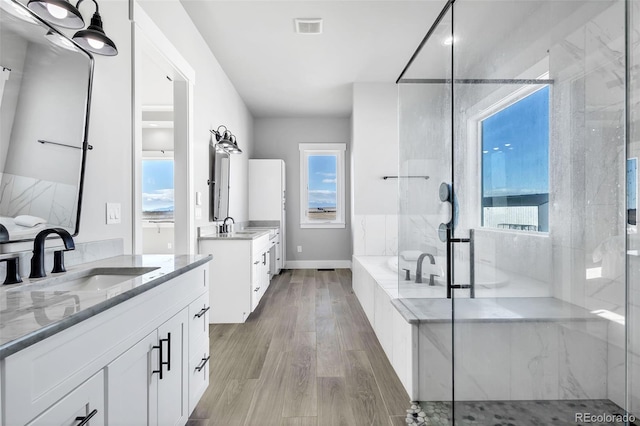 7668 Buckskin Ranch Vw, Peyton, CO 80831 - full bathroom with a marble finish shower, two vanities, a sink, visible vents, and wood finished floors