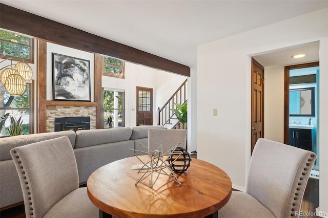 dining area featuring a fireplace, beam ceiling, and sink