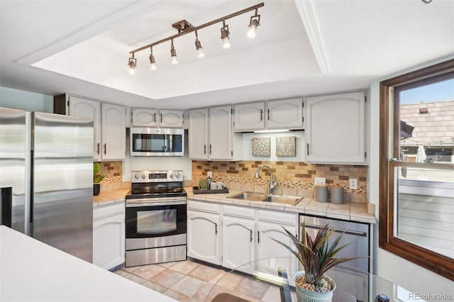 kitchen with sink, a raised ceiling, backsplash, light tile patterned floors, and appliances with stainless steel finishes