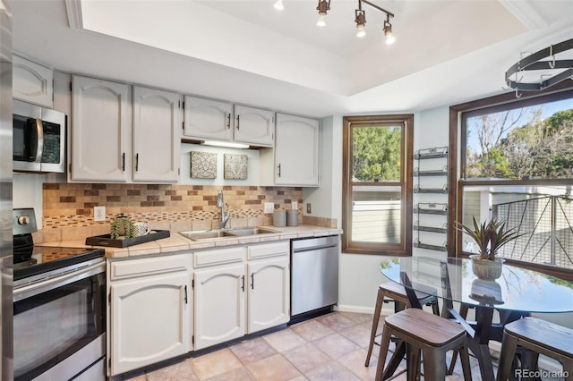 kitchen featuring stainless steel appliances, white cabinetry, tile counters, and sink