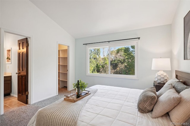 carpeted bedroom with a walk in closet, ensuite bathroom, and lofted ceiling