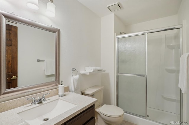 bathroom with vanity, a shower with shower door, and toilet