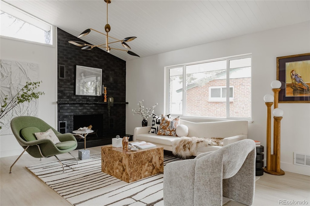 living room featuring vaulted ceiling, a chandelier, a fireplace, wood finished floors, and visible vents