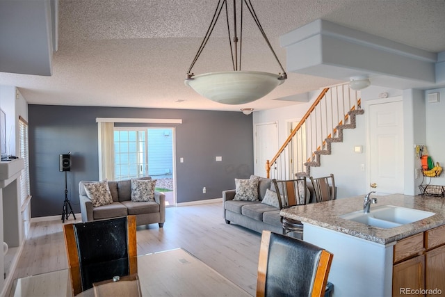 living room with sink, light hardwood / wood-style flooring, and a textured ceiling