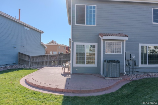 rear view of house featuring cooling unit, a yard, and a patio