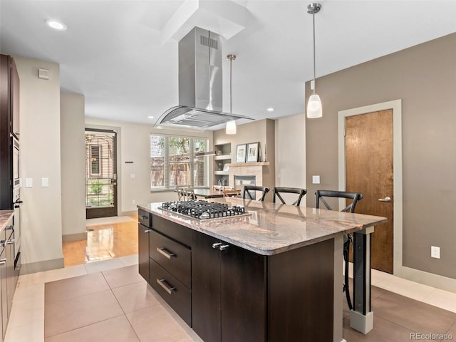 2741 Java Ct, Denver, CO 80211 - kitchen featuring stainless steel gas cooktop, island range hood, a kitchen bar, light tile patterned floors, and a kitchen island