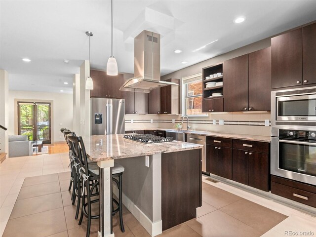 2741 Java Ct, Denver, CO 80211 - kitchen with stainless steel appliances, island range hood, dark brown cabinets, a kitchen bar, and light tile patterned floors