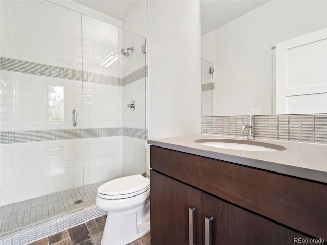 bathroom featuring vanity, toilet, a shower with shower door, and backsplash