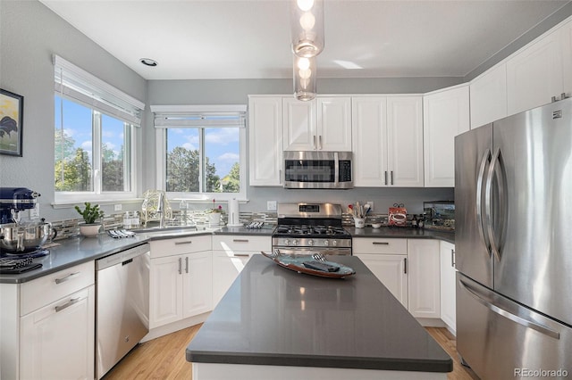7696 S Hudson Way, Centennial, CO 80122 - kitchen featuring appliances with stainless steel finishes, dark countertops, a sink, white cabinetry, and a center island
