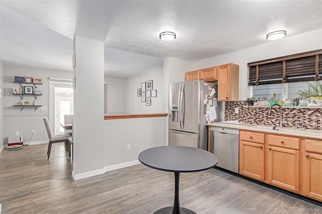 1371 W 133rd Way, Denver, CO 80234 - kitchen with appliances with stainless steel finishes, a textured ceiling, tasteful backsplash, light wood-style flooring, and light brown cabinetry