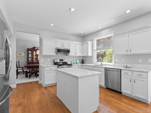 16362 Oakmoor Pl, Parker, CO 80134 - kitchen with stainless steel appliances, white cabinets, a center island, light wood-style floors, and recessed lighting