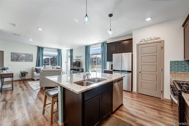 kitchen featuring a healthy amount of sunlight, appliances with stainless steel finishes, light wood-style floors, and a sink