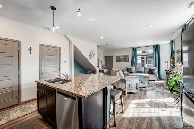 kitchen with light stone counters, visible vents, light wood-style flooring, a sink, and stainless steel dishwasher