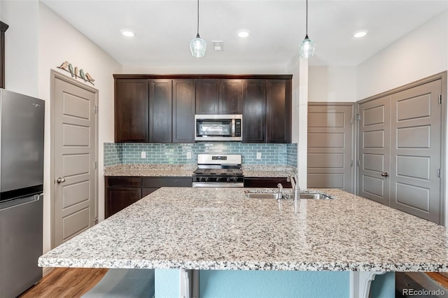 kitchen featuring a sink, light stone counters, a breakfast bar, and stainless steel appliances