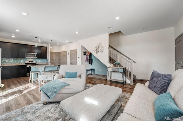 living room featuring stairway, recessed lighting, baseboards, and light wood finished floors