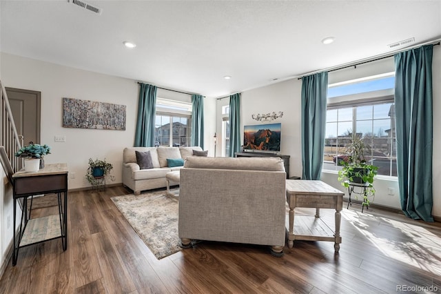 living area with dark wood-type flooring, stairway, baseboards, and visible vents