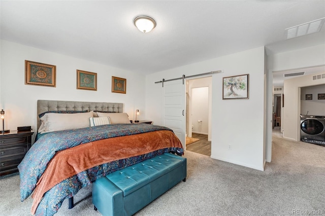 bedroom featuring a barn door, carpet flooring, visible vents, and washer / dryer