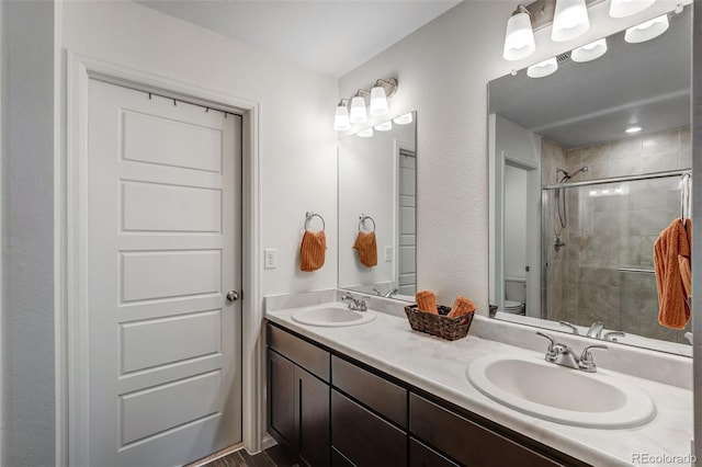 bathroom with double vanity, toilet, a stall shower, and a sink