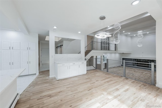 kitchen with white cabinets, light hardwood / wood-style flooring, a baseboard heating unit, and pendant lighting