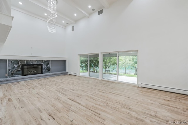 unfurnished living room featuring beam ceiling, high vaulted ceiling, light hardwood / wood-style flooring, and a premium fireplace