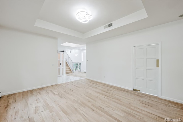 spare room featuring a raised ceiling and light hardwood / wood-style flooring