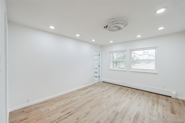 spare room with baseboard heating and light wood-type flooring