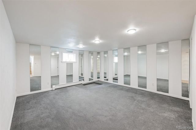 carpeted empty room featuring a baseboard heating unit