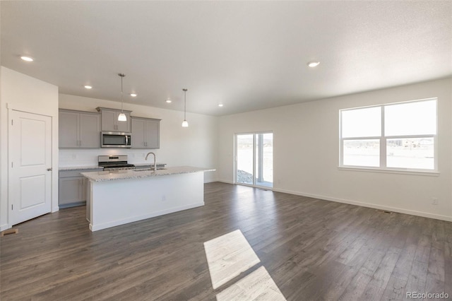 6721 Raven Ridge Ter, Colorado Springs, CO 80925 - kitchen with appliances with stainless steel finishes, gray cabinets, a sink, dark wood-type flooring, and a center island with sink