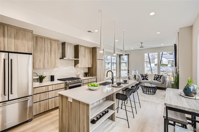 2323 S High St, Denver, CO 80210 - kitchen with appliances with stainless steel finishes, wall chimney exhaust hood, modern cabinets, a kitchen bar, and light countertops