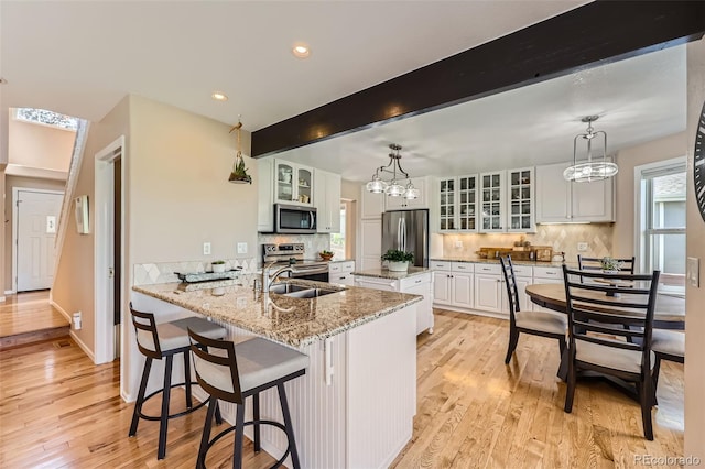 9733 Quay Loop, Broomfield, CO 80021 - kitchen with appliances with stainless steel finishes, a center island, light wood-style floors, backsplash, and recessed lighting