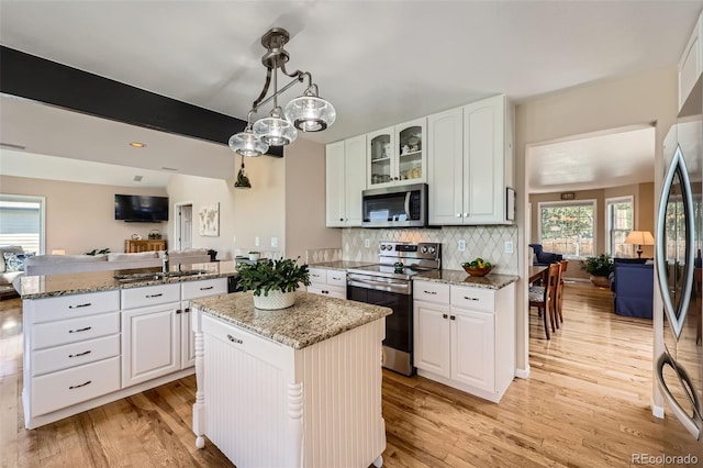 9733 Quay Loop, Broomfield, CO 80021 - kitchen featuring appliances with stainless steel finishes, a peninsula, light wood-type flooring, decorative backsplash, and glass insert cabinets