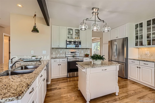 9733 Quay Loop, Broomfield, CO 80021 - kitchen with appliances with stainless steel finishes, light wood finished floors, tasteful backsplash, light stone counters, and white cabinets