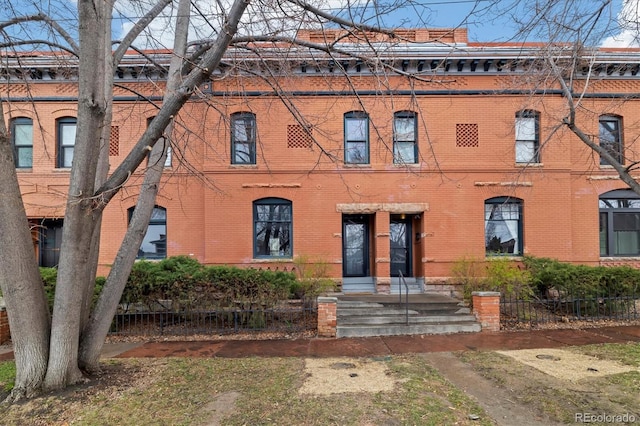 view of front of home with brick siding and fence