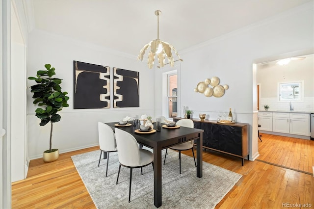dining room featuring an inviting chandelier, light wood-style floors, and crown molding
