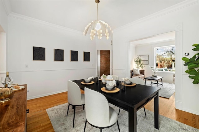 dining room with baseboards, wood finished floors, an inviting chandelier, and crown molding