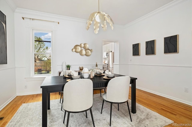 dining space featuring visible vents, crown molding, baseboards, a chandelier, and light wood-style flooring