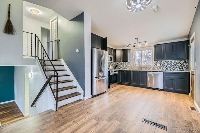 kitchen featuring track lighting, decorative backsplash, light hardwood / wood-style flooring, and appliances with stainless steel finishes