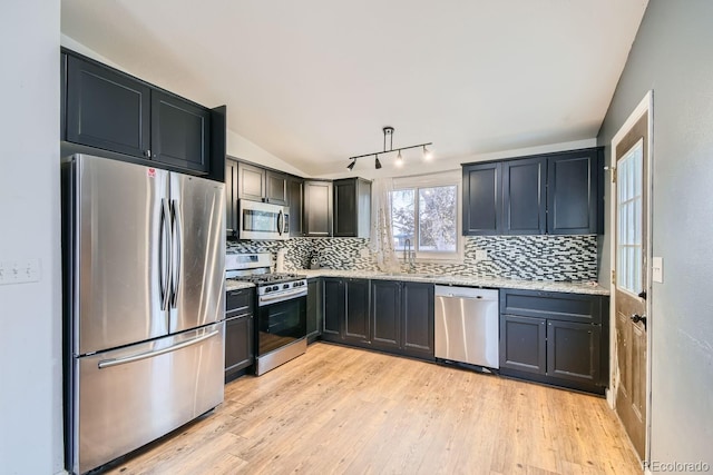 kitchen with tasteful backsplash, light stone counters, light hardwood / wood-style floors, and stainless steel appliances