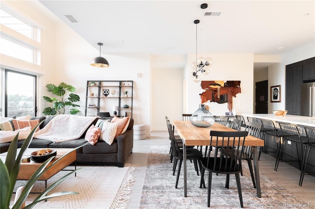 dining space with light hardwood / wood-style flooring and a chandelier